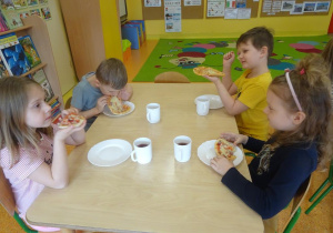Czwórka dzieci je pizzę.